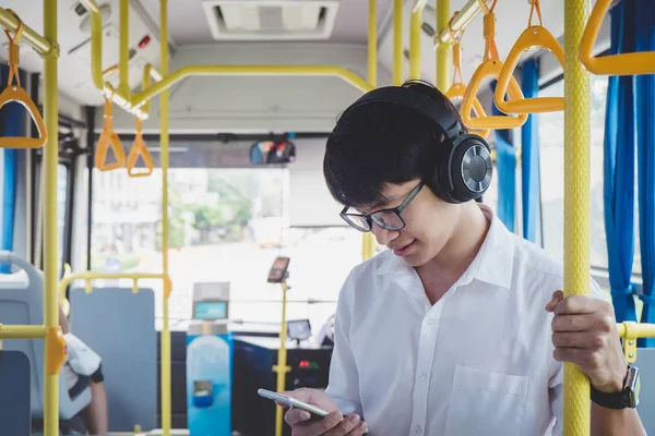Asijský mladík cestovatel stojící na autobus, poslech hudby na — Stock fotografie