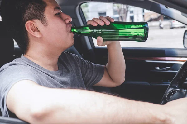 Joven asiático hombre conduce un coche con borracho un botella de cerveza detrás —  Fotos de Stock