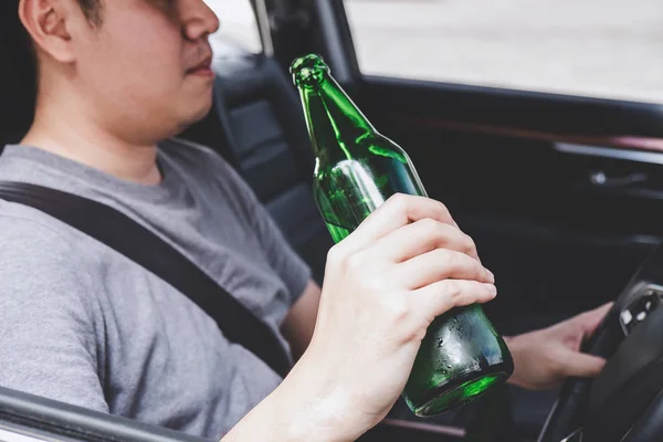 Jeune homme asiatique conduit une voiture avec ivre une bouteille de bière derrière — Photo