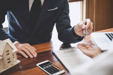 Emlakçı Satış yöneticisi müşteriye dosyalama anahtarları tutan 