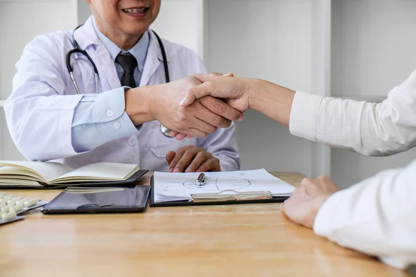 Médico masculino profesional en bata blanca estrechando la mano con la mujer — Foto de Stock