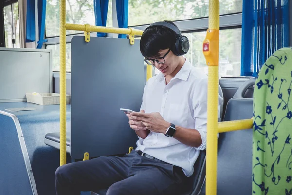 Mladý asijský cestovatel, který sedí na autobusu a poslouchá hudbu na — Stock fotografie
