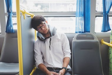 Bir otobüse oturan ve pill uyuyan genç Asyalı adam traveler