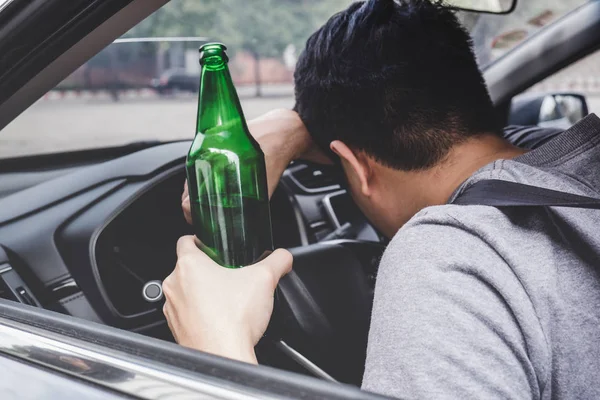 Joven asiático hombre conduce un coche con borracho un botella de cerveza y fal —  Fotos de Stock