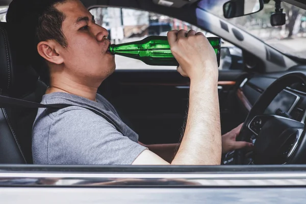 Joven asiático hombre conduce un coche con borracho un botella de cerveza detrás —  Fotos de Stock