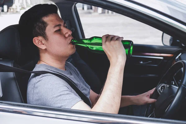 Joven asiático hombre conduce un coche con borracho un botella de cerveza detrás —  Fotos de Stock