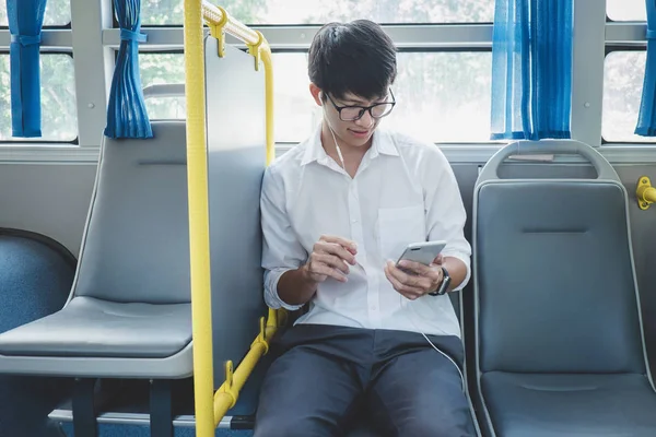 Jovem asiático viajante sentado em um ônibus ouvindo música em — Fotografia de Stock