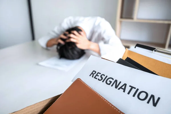 Images of packing up all his personal belongings and files into a brown cardboard box, Businessman has frustrated and stressed to resignation and signing cancellation contract letter in office.