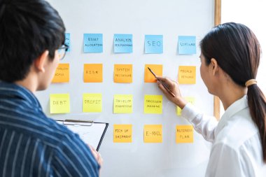 İki yaratıcı iş adamı toplantı ve planlama fikri paylaşmak, veri grafiklerini analiz etmek ve takım çalışması stratejisi beyin fırtınası ile grafikleri paylaşmak için gemiye yapışkan notlar yazdılar..