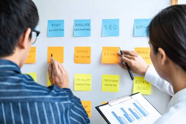 İki yaratıcı iş adamı toplantı ve planlama fikri paylaşmak, veri grafiklerini analiz etmek ve takım çalışması stratejisi beyin fırtınası ile grafikleri paylaşmak için gemiye yapışkan notlar yazdılar..