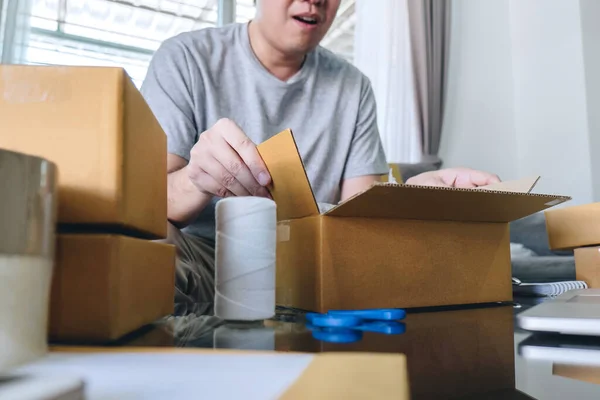 小企业包裹航运 快乐的人打开网上购物包装盒与包裹 而坐在沙发上在家里 — 图库照片