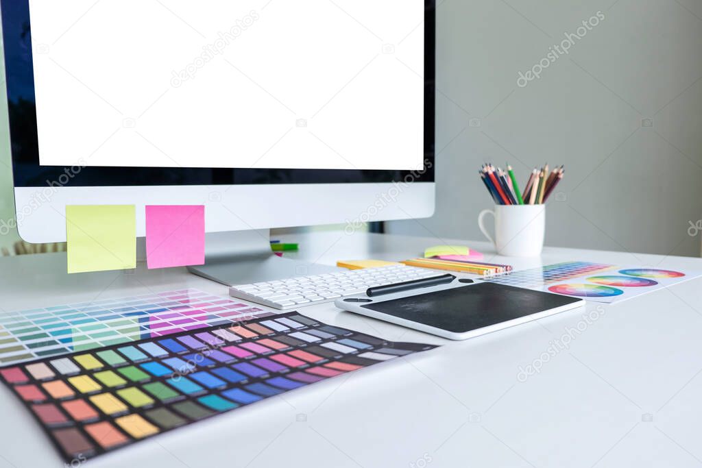 Modern office workplace with tablet, Graphic designer and color swatch samples at workplace.