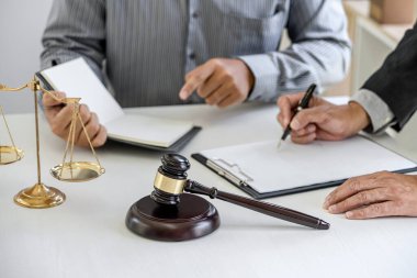 Mahkemede çalışan erkek avukat veya avukat, emlak, hukuk ve hukuk hizmetleri kavramının sözleşme belgeleriyle istişarede bulunarak müvekkilleriyle görüşür..