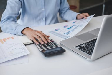 Yeni iş stratejisi ve işyerindeki piyasa büyümesi projesi için finansal belge veri grafiğinin istatistiklerini hesaplayarak dizüstü bilgisayarda çalışan ve analiz eden profesyonel iş kadını.