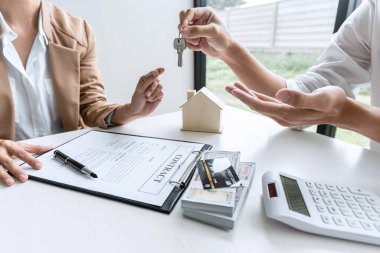 Emlak acentesinin kira kontratı ve konut sigortası için ipotek kredisi teklifiyle ilgili satış sözleşmesini imzaladıktan sonra ev anahtarlarını müşteriye vermesi.