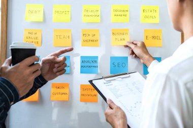 İki yaratıcı iş adamı toplantı ve planlama fikri paylaşmak, veri grafiklerini analiz etmek ve takım çalışması stratejisi beyin fırtınası ile grafikleri paylaşmak için gemiye yapışkan notlar yazdılar..