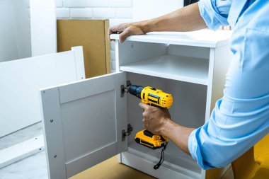 Evinde tadilat yapan bir adam dolaptaki matkapla odun deliyor..