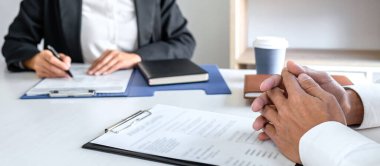 Yönetici, iş görüşmesi sırasında özgeçmiş okurken, işveren, genç erkek iş arayan kişiden ofiste iş görüşmesi yapmasını ister..