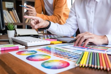 Renk seçimi ve renk örnekleri üzerinde çalışan iki iş arkadaşı yaratıcı grafik tasarımcısı, çalışma araçları ve aksesuarlarla iş yerindeki grafik tabletine çizim yapıyor.