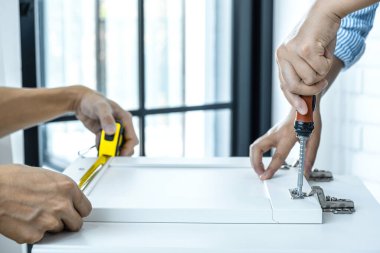 Ev işlerinde, iş arkadaşlarıyla tadilat yapan, ahşap zemini ve iç tasarım konseptini ölçen bir zanaatkar..