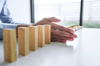 İş hayatında risk ve strateji, iş kadınlarının eli, Domino hattına düşmekten üç yol arasındaki tahta bloğu durdurur..
