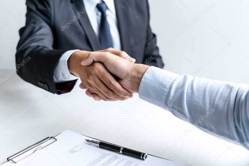 Greeting new colleagues, Handshake while job interviewing, male candidate shaking hands with Interviewer or employer after a job interview, employment and recruitment concept.