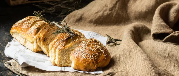 Freshly baked wheat bread on natural linen napkin and bag. Homemade bakery. Still life of bread. Slice of gold rustic crusty loave of bread. Banner layout — Stock Photo, Image