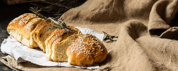 Freshly baked wheat bread on natural linen napkin and bag. Homemade bakery. Still life of bread. Slice of gold rustic crusty loave of bread. Banner layout — Stock Photo, Image