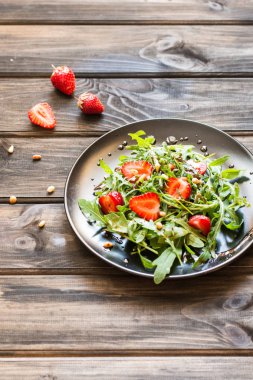 Taze salata roka ve Balsamik Sos ve çam fıstığı ile strawbery. Vejetaryen yiyecekler. Çilek salatası. Vitamini yiyecek, diyet salata ahşap arka planda siyah plaka üzerinde.