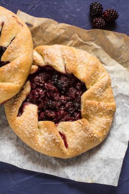 Yaz Galette'ye çilek, ahududu, yaban mersini, böğürtlen, elma ve huysuz şeker vejetaryen hamur üzerinde mavi arka plan ile. Yaz gıda, parşömen kağıt üzerine yaz pasta. Açık pasta. Vegan gıda.