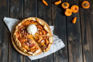Ev yapımı kayısı Galette'ye ahşap masa, üstten görünüm üzerinde taze organik apricotes ile yaptı. Pişirme işlemi. Açık pasta, kayısı tart. Meyve bak lezzetli yaz tatlı şeftali Galette'ye bir plaka ışık mavi kayrak, taş veya beton arka plan üzerinde. Üstten görünüm.