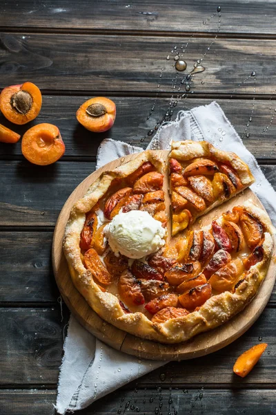 Ev yapımı kayısı Galette'ye ahşap masa, üstten görünüm üzerinde taze organik apricotes ile yaptı. Pişirme işlemi. Açık pasta, kayısı tart. Meyve ekmek. Sıcak pasta ile soğuk dondurma.