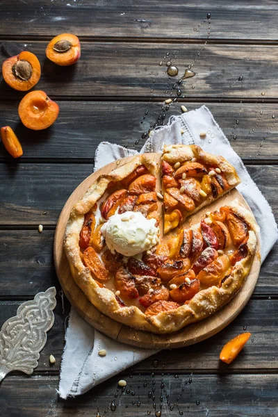 Ev yapımı kayısı Galette'ye ahşap masa, üstten görünüm üzerinde taze organik apricotes ile yaptı. Pişirme işlemi. Açık pasta, kayısı tart. Meyve ekmek. Sıcak pasta ile soğuk dondurma.