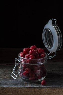 Ahududu koyu ahşap arka plan üzerinde bir cam kavanoza. Ahududu arka plan. Sağlıklı gıda kavramı. Taze organik çilek
