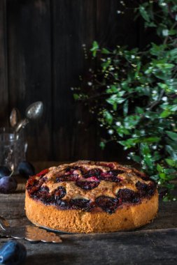 Eski ahşap zemin üzerine ev yapımı erik turtası. Vintage kaşık. Gıda natürmort. Erik tart. Sonbaharda hasat. Eski moda mutfak. Pasta kısmı. Erik fırını. Rustik açık pasta.