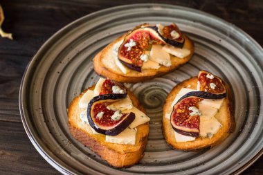 Ricotta, taze incir, ceviz ve bal siyah zemin üzerinde rustik ahşap tahta üzerinde sandviçle görünümü top. Bruschetta incir ile. Aperitive. Akdeniz mutfağı. Crostini.