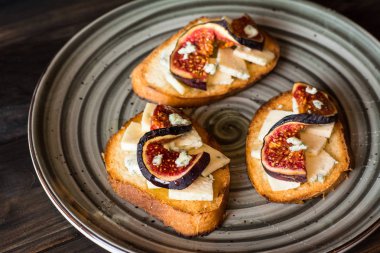Ricotta, taze incir, ceviz ve bal siyah zemin üzerinde rustik ahşap tahta üzerinde sandviçle görünümü top. Bruschetta incir ile. Aperitive. Akdeniz mutfağı. Crostini.