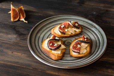 Ricotta, taze incir, ceviz ve bal siyah zemin üzerinde rustik ahşap tahta üzerinde sandviçle görünümü top. Bruschetta incir ile. Aperitive. Akdeniz mutfağı. Crostini.
