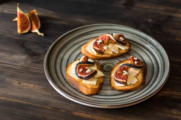 Ricotta, taze incir, ceviz ve bal siyah zemin üzerinde rustik ahşap tahta üzerinde sandviçle görünümü top. Bruschetta incir ile. Aperitive. Akdeniz mutfağı. Crostini.