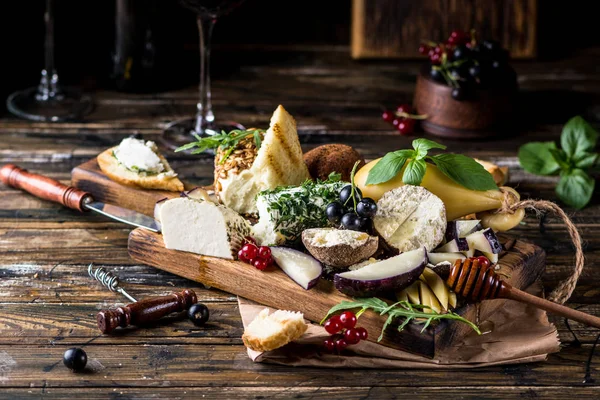 Selecção de aperitivos de queijo. Groselha vermelha, mel, manjericão, uvas e nozes em tábua de madeira rústica sobre fundo de concreto de madeira, vista superior. Belper Knolle, queijo de cabra, Scamorza. Tabuleiro de queijo, prato de queijo — Fotografia de Stock