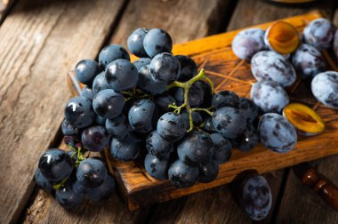 Eski ahşap bir masada üzümler. Mavi üzüm. Siyah üzüm. Üzüm üzümü. Yemek dolu bir hayat..