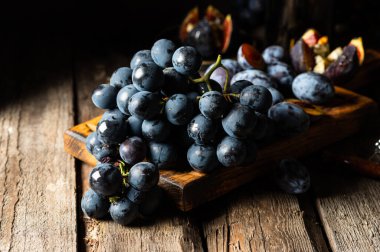 Eski ahşap bir masada üzümler. Mavi üzüm. Siyah üzüm. Üzüm üzümü. Yemek dolu bir hayat..