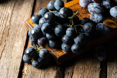Eski ahşap bir masada üzümler. Mavi üzüm. Siyah üzüm. Üzüm üzümü. Yemek dolu bir hayat..