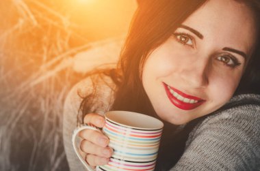 Genç güzel kız gülümseyerek içecek bir fincan sıcak kazak rahat portre tutar.