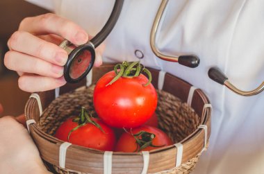 Doktor stetoskop bir tutar ve domates çekleri yakın çekim