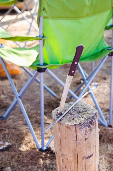 Folding chair and knife on the stump camping concept