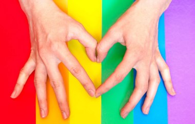Eller gökkuşağı lgbt arka plan üzerinde kalp jest göstermek