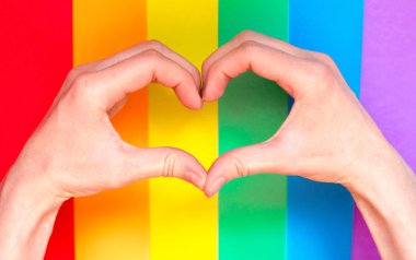 Eller gökkuşağı lgbt arka plan üzerinde kalp jest göstermek