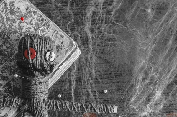 Voodoo-pop met naalden en oude boek op houten achtergrond bedekt met SpiderWeb — Stockfoto