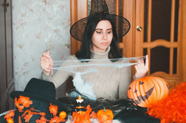 Giovane donna in cappello strega si prepara per Halloween e mantiene ragnatela falso — Foto Stock